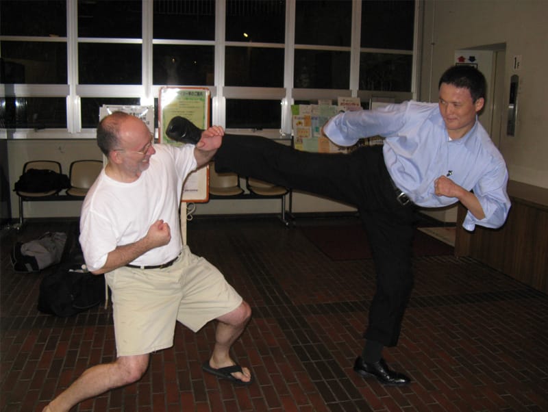 Michael Busha and a fellow karateka in street clothes demonstrating a high kick